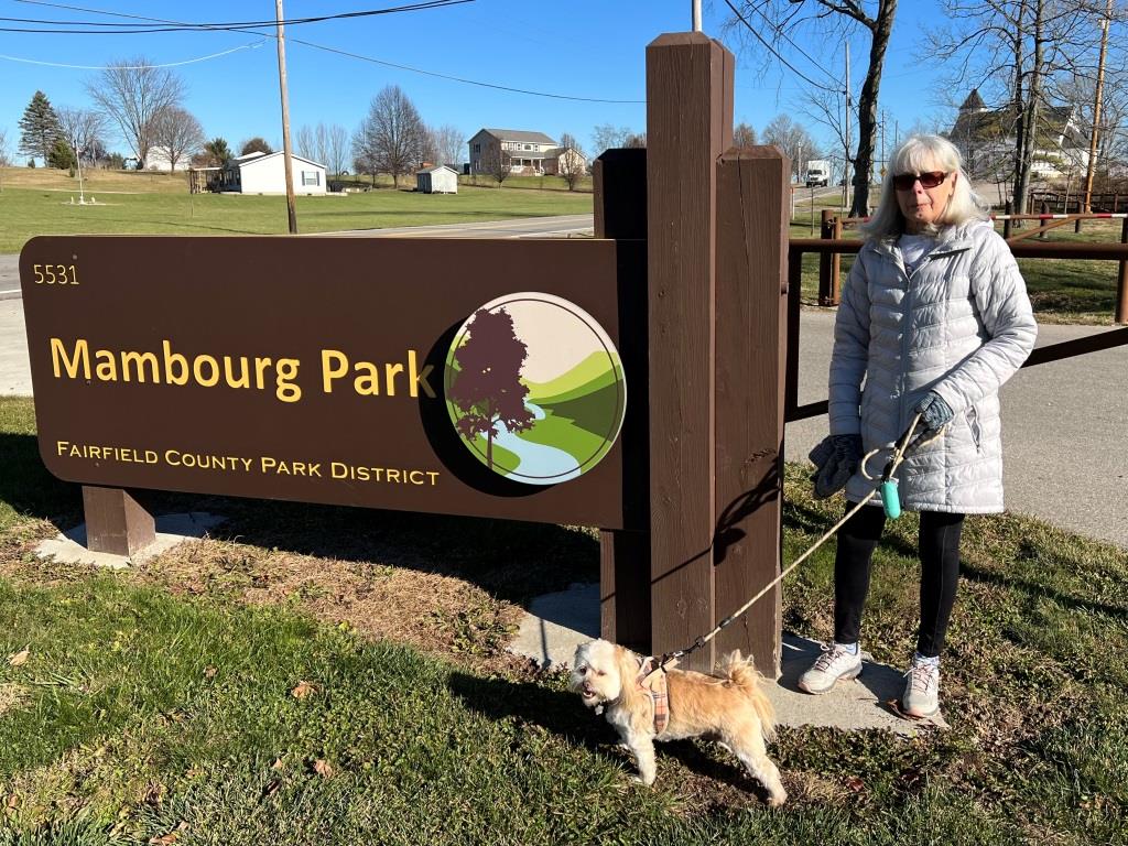 woman with dog on leash near Mambourg Park entrance sign